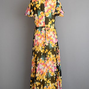 May include: A long black maxi dress with a floral print in shades of yellow, pink, and white. The dress has a ruffled neckline and short sleeves.
