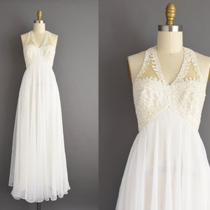 May include: A white sleeveless maxi dress with a sheer lace bodice and a flowing skirt.