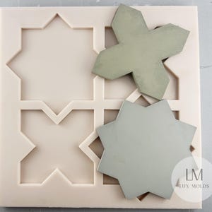 May include: A light pink silicone mold with geometric star and cross shapes, alongside two gray concrete tiles in matching designs. The mold features a grid pattern, and the logo "LM LUX MOLDS" is visible.