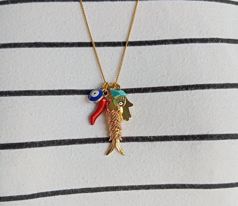 Puede incluir: Collar de oro con un dije de pescado, un chile rojo y un dije de ojo azul.