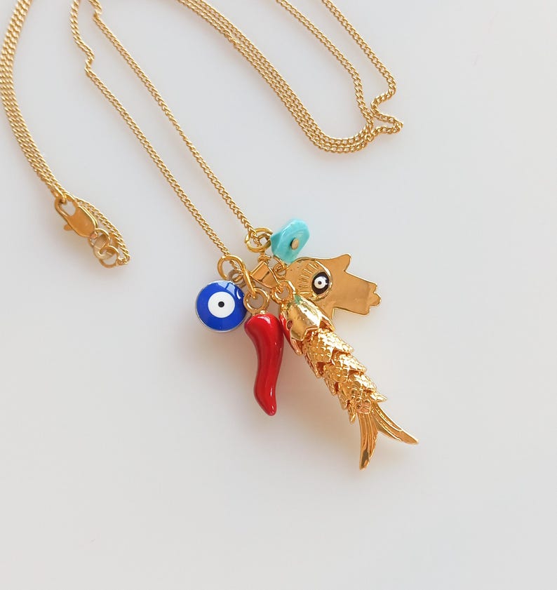 Puede incluir: Collar de cadena dorada con m&uacute;ltiples dijes, incluyendo un chile rojo, un ojo turco azul, una cuenta turquesa y un dije de pez dorado.