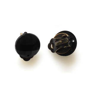 May include: A pair of black clip-on earrings with a gold metal clasp. The earrings are round and have a smooth, glossy finish.
