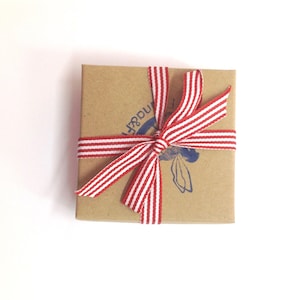 May include: A small, brown cardboard box with a red and white striped ribbon tied in a bow. The box has a blue stamp with the word "Wonder" on it.