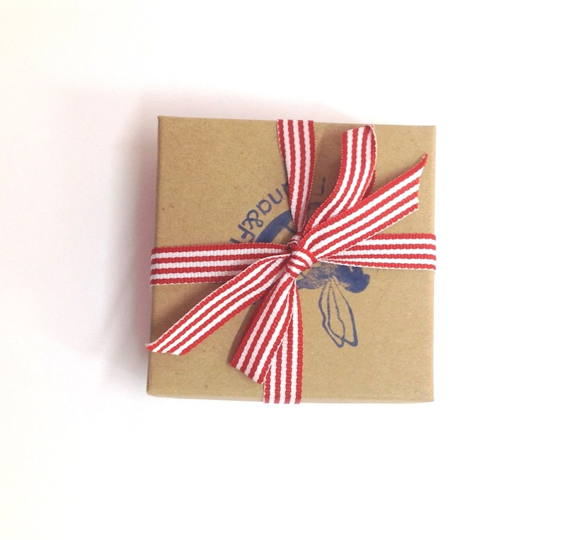 May include: A small, brown cardboard box with a red and white striped ribbon tied in a bow. The box has a blue stamp with the word "Wonder" on it.