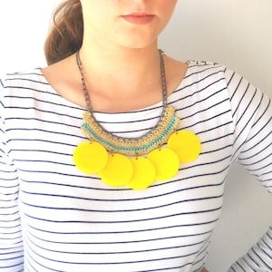 May include: A yellow and turquoise crocheted necklace with large yellow circle pendants.