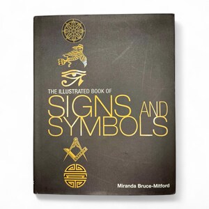 May include: The Illustrated Book of Signs and Symbols by Miranda Bruce-Mitford. The book cover features a dark gray background with gold illustrations of various symbols, including a wheel, a bird, an eye, a square and compass, and a circle with a square inside.