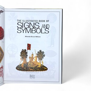 May include: The Illustrated Book of Signs and Symbols by Miranda Bruce-Mitford, a book cover with a colorful illustration of a woman sitting on a throne with a unicorn and two lions.