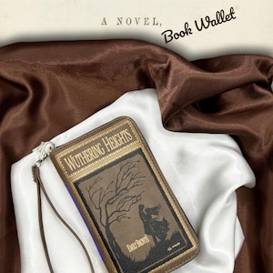 Wuthering Heights book wallet laying flat on ivory satin with front cover facing up, highlighting full cover artwork and moody color tones