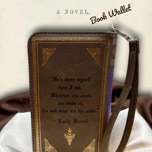 Back view of Wuthering Heights book wallet displayed on ivory satin, featuring the printed quote and attached wristlet strap