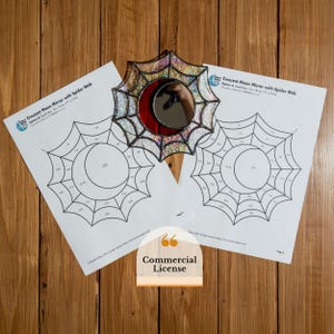 Può includere: Uno specchio decorativo a forma di mezzaluna con un design a ragnatela, con una mezzaluna rossa e una superficie riflettente. Lo specchio è circondato da una cornice a forma di ragnatela. Sono visibili anche due fogli di carta con un disegno a ragnatela e luna. Il testo "Commercial License" è anche visibile.