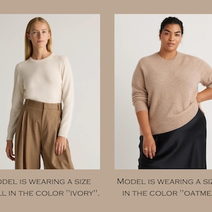 May include: Two models wearing sweaters. The model on the left is wearing a white sweater and the model on the right is wearing a beige sweater. The text below the images says "MODEL IS WEARING A SIZE SMALL IN THE COLOR "IVORY"." and "MODEL IS WEARING A SIZE 2X IN THE COLOR "OATMEAL"."
