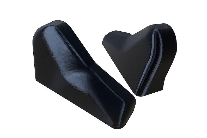 Puede incluir: Dos objetos negros angulares con un acabado liso y brillante. Uno tiene forma de cu&ntilde;a, el otro es m&aacute;s compacto y con forma de coraz&oacute;n. Los objetos parecen estar hechos de un material s&oacute;lido, posiblemente pl&aacute;stico o resina.
