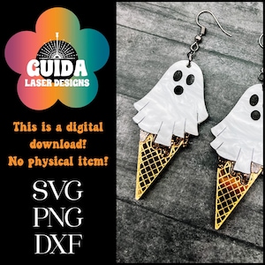 May include: A pair of white ghost ice cream cone earrings with gold glitter accents. The earrings are on a wooden background.