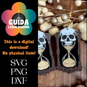 May include: A pair of earrings featuring a skull above an hourglass design. The earrings are black with a light blue skull and a tan hourglass. The earrings are hanging from gold-colored hooks. The image also includes the text "GUIDA LASER DESIGNS" and "This is a digital download! No physical item! SVG PNG DXF."