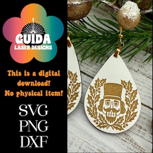 Puede incluir: Pendientes blancos en forma de lágrima con un diseño de cascanueces dorado y ganchos dorados. Los pendientes están decorados con un patrón de hojas y bayas de acebo. La imagen incluye texto: "¡Esta es una descarga digital! ¡Sin artículo físico!"