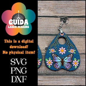 May include: A pair of blue wooden earrings shaped like a witch's board with a butterfly and floral design. The earrings have a silver hook.