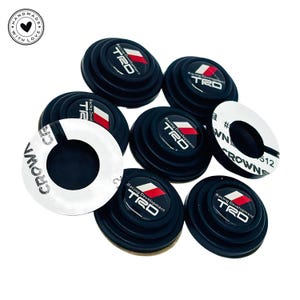 May include: A collection of black TRD Racing Development car accessories. Each piece has a red and white logo. Some pieces have a white sticker with the word "CROWN" and the number "512". The image also includes a "HANDMADE WITH LOVE" logo.