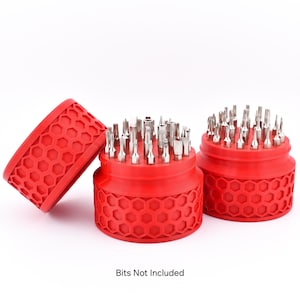 Op de afbeelding: Rode bithouders met een honingraatpatroon, elk met diverse zilveren schroevendraaierbits. Eén houder is open en toont de bits. De tekst "Bits Not Included" staat onderaan.