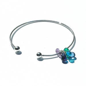 May include: A silver bangle bracelet with a cluster of colourful gemstone charms hanging from it. The charms are in shades of purple, green, and blue.