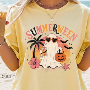 May include: Yellow t-shirt with a "Summerween" graphic. The design features a ghost wearing heart-shaped sunglasses, holding a drink and a jack-o'-lantern, with a palm tree, hibiscus, and bats. The word "butter" is printed on the bottom left.