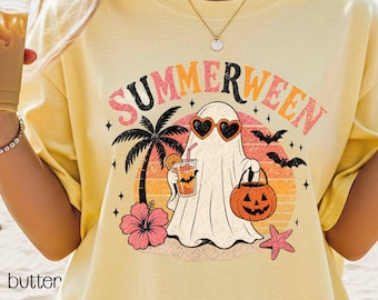 May include: Yellow t-shirt with a "Summerween" graphic. The design features a ghost wearing heart-shaped sunglasses, holding a drink and a jack-o'-lantern, with a palm tree, hibiscus, and bats. The word "butter" is printed on the bottom left.