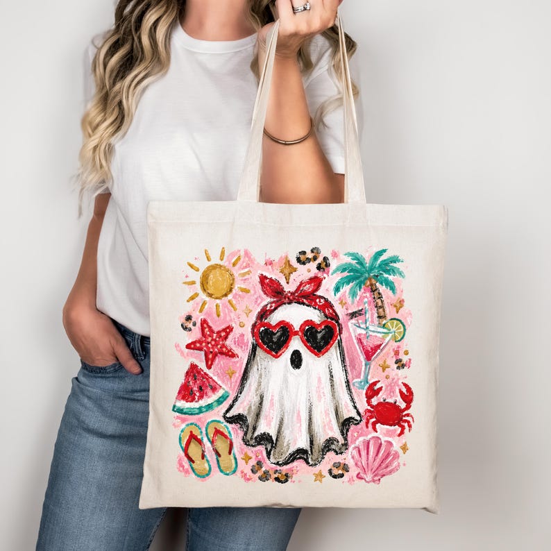 May include: A cream-colored tote bag featuring a whimsical design of a ghost wearing heart-shaped sunglasses and a red bandana. The design includes a sun, palm tree, cocktail, watermelon, starfish, and crab, evoking a summer theme.