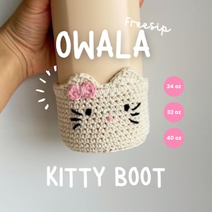 May include: A crocheted white kitty boot cozy with pink bows and black eyes. The cozy is designed to fit a 24 oz, 32 oz, or 40 oz bottle. The text "OWALA KITTY BOOT" is written below the cozy.