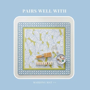 May include: A square mahjong mat featuring a white and blue dotted border, a lime green inner frame, and a central pattern of white line-drawn leaves on a lime green background. The text PAIRS WELL WITH and MAHJONG MAT appear on the mat.