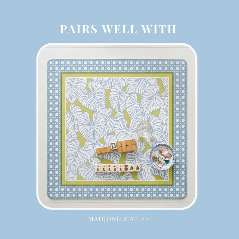 May include: A square mahjong mat featuring a white and blue dotted border, a lime green inner frame, and a central pattern of white line-drawn leaves on a lime green background. The text PAIRS WELL WITH and MAHJONG MAT appear on the mat.