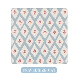 May include: A square travel-size mat with a repeating pattern of red floral motifs within white diamond shapes against a light blue background. The mat has rounded corners and the text "TRAVEL SIZE MAT" is at the bottom.