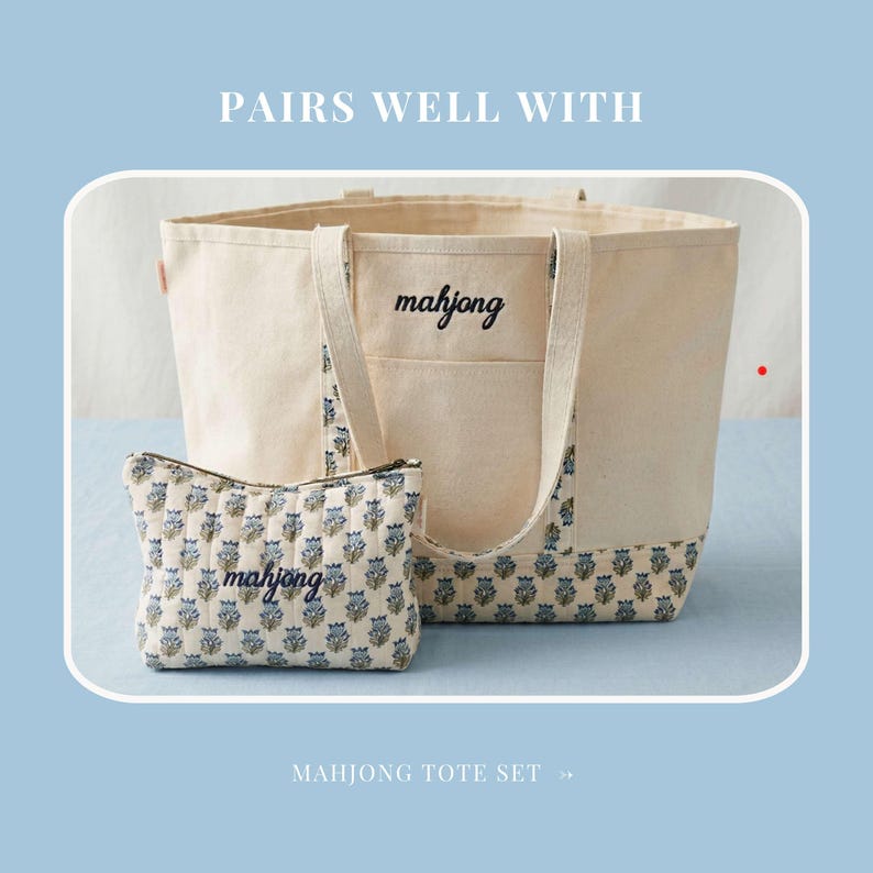 May include: A canvas tote bag and matching zippered pouch set. The tote bag is beige with "mahjong" embroidered on the front. The pouch and the bottom of the tote feature a blue floral pattern. The text "PAIRS WELL WITH" and "MAHJONG TOTE SET" are also visible.