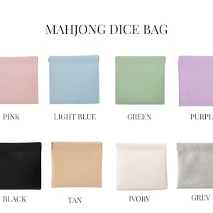 May include: A collection of eight small, square Mahjong dice bags in various colors: pink, light blue, green, purple, black, tan, ivory, and grey. Each bag has a simple, folded top design and is labeled with its color name.
