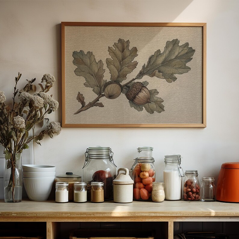 May include: A framed botanical print of oak leaves and acorns hangs above a countertop with various glass jars and containers. The jars hold ingredients like tomatoes, flour, and spices. A vase of dried flowers and a bright orange container are also present.