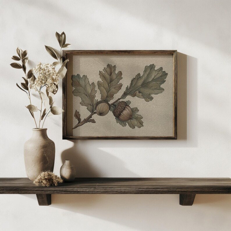 May include: A framed botanical print featuring an oak branch with leaves and acorns. The artwork is in muted green and brown tones, set against a beige background. The frame is a dark wood, and the print is displayed on a wooden shelf.