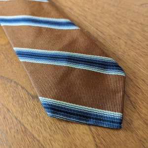 May include: A brown striped tie with blue and white stripes. The tie is made of a woven fabric.