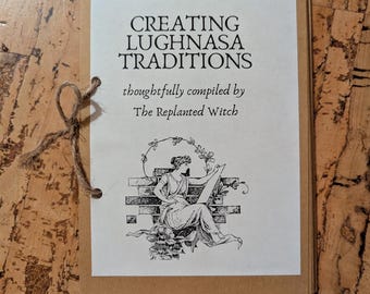 Pode incluir: Um pequeno livreto artesanal com capa castanha e página interior branca. A capa diz "CREATING LUGHNASA TRADITIONS" com o texto "thoughtfully compiled by The Replanted Witch." Uma ilustração de uma mulher está na frente.
