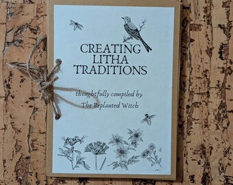 Pode incluir: Um diário artesanal com o título "CREATING LITHA TRADITIONS" e ilustrações de um pássaro, abelhas e flores. O diário é encadernado com barbante e repousa sobre uma superfície castanha texturizada.
