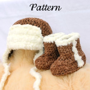 May include: A brown and white crocheted hat with ear flaps and matching brown and white crocheted booties. The hat and booties are sitting on a fuzzy brown surface.