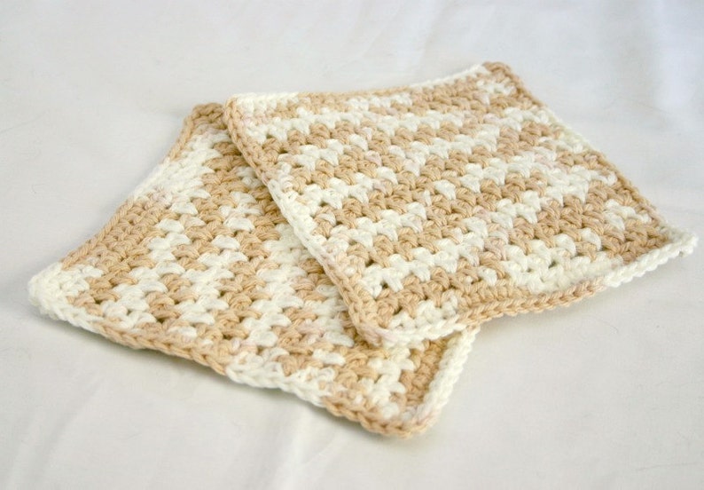 May include: Two crocheted kitchen dishcloths in a beige and white checkered pattern.