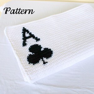May include: White crochet blanket with a black crochet design of the Ace of Clubs.