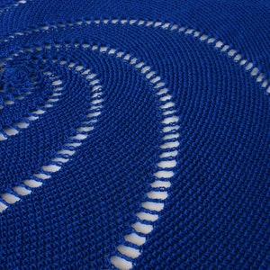 May include: A close-up of a blue crocheted doily with a circular pattern. The doily has a delicate, lacy design with openwork details.