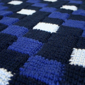 May include: A close-up of a blue and white crocheted blanket with a checkered pattern.