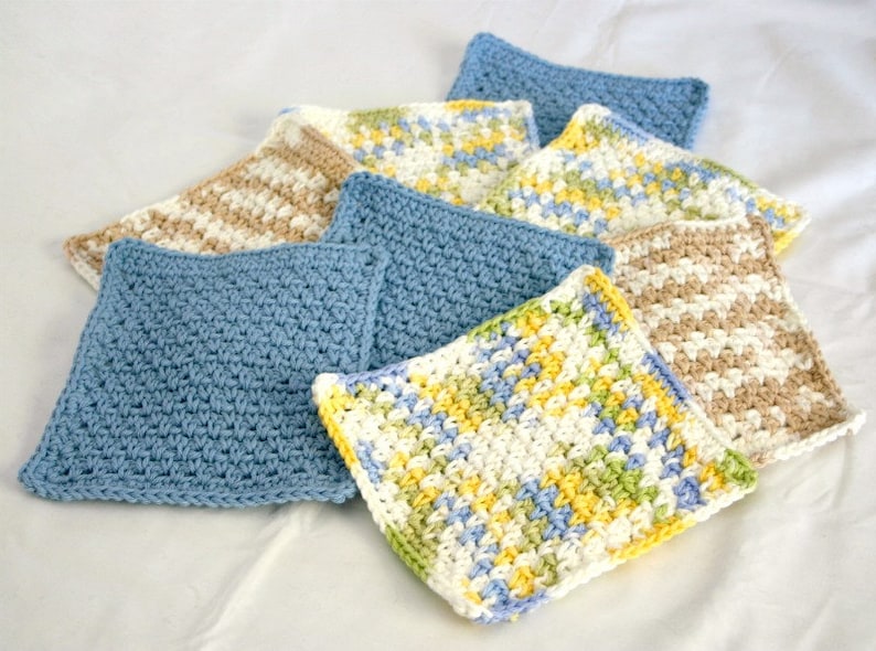 May include: A stack of six crocheted dishcloths in various colors and patterns, including blue, white, yellow, and brown.