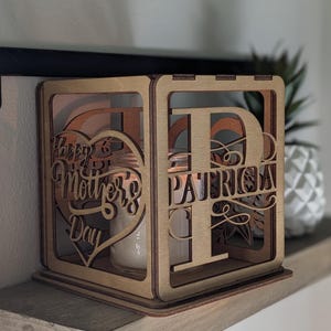 May include: A wooden box with a heart cutout that says "Happy Mother's Day" and a letter "P" cutout with the name "Patricia" underneath. The box is designed to hold a candle or other small object.