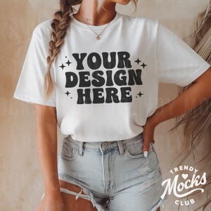 May include: White t-shirt with short sleeves and a crew neck. The shirt has the text "YOUR DESIGN HERE" in black with stars on either side of the text.