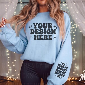 May include: A light blue sweatshirt with the text "YOUR DESIGN HERE" in black on the front and the text "YOUR DESIGN HERE" in black on the sleeve.