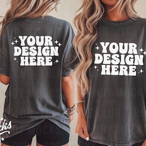 以下が含まれることがあります： レトロなフォントで「YOUR DESIGN HERE」と書かれた白いグラフィックが施された、ダークグレーのオーバーサイズTシャツです。