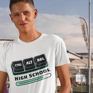 Könnte beinhalten: Weißes T-Shirt mit einer Grafik von Computertasten mit der Aufschrift "CTRL", "ALT" und "DEL" über dem Text "HIGH SCHOOL" mit einer Fortschrittsanzeige mit der Aufschrift "GRADUATION LOADING..."