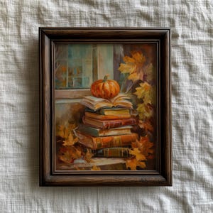 May include: A framed painting depicts a stack of books with an open book on top, and a small orange pumpkin. Autumn leaves surround the books and frame. The window in the background has a blue-green hue.