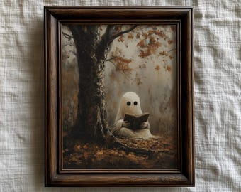 May include: A framed print depicts a ghost reading a book under a tree. The artwork features a brown wooden frame, a white ghost with black eyes, and a tree with autumn leaves. The color palette is muted with brown and beige tones.